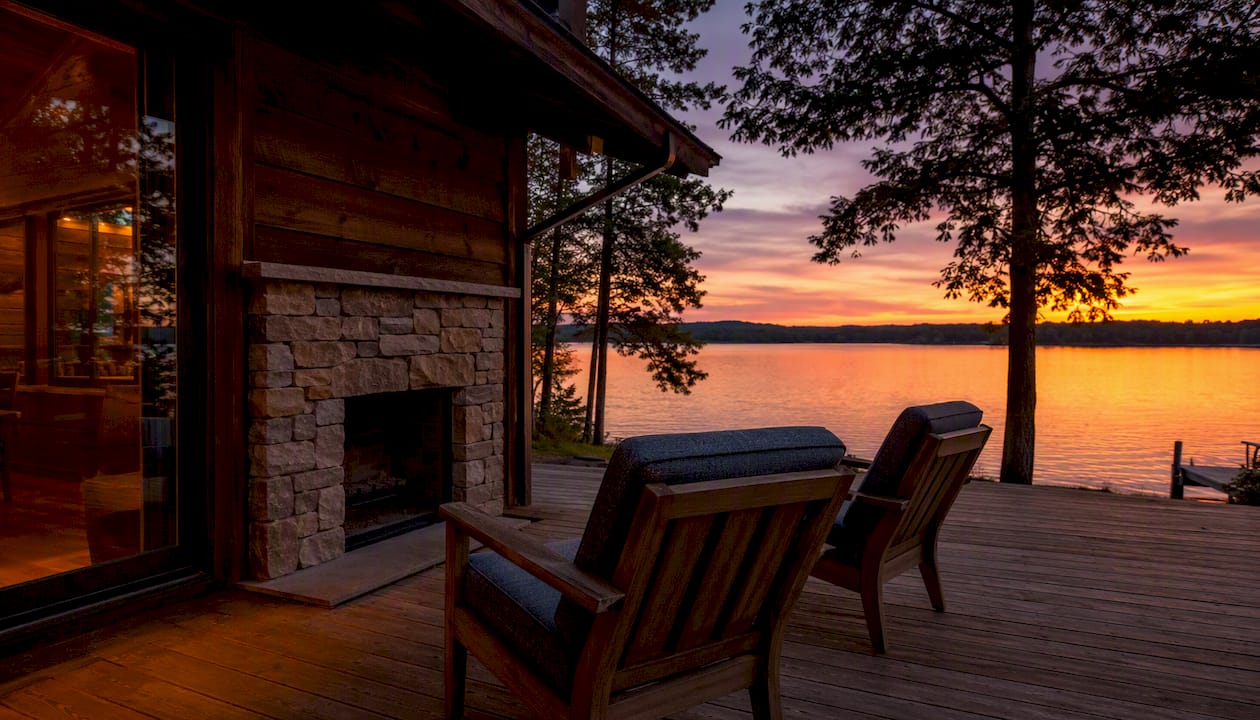 Lakeside cabin deck with fireplace at sunset