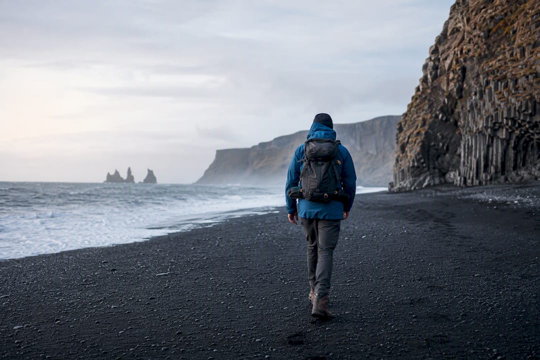 Tourist walking on black sand beach in Iceland