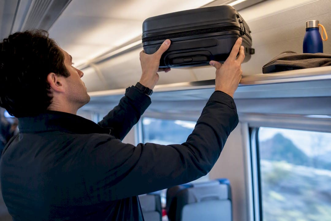 Traveler stowing luggage on an intercity train