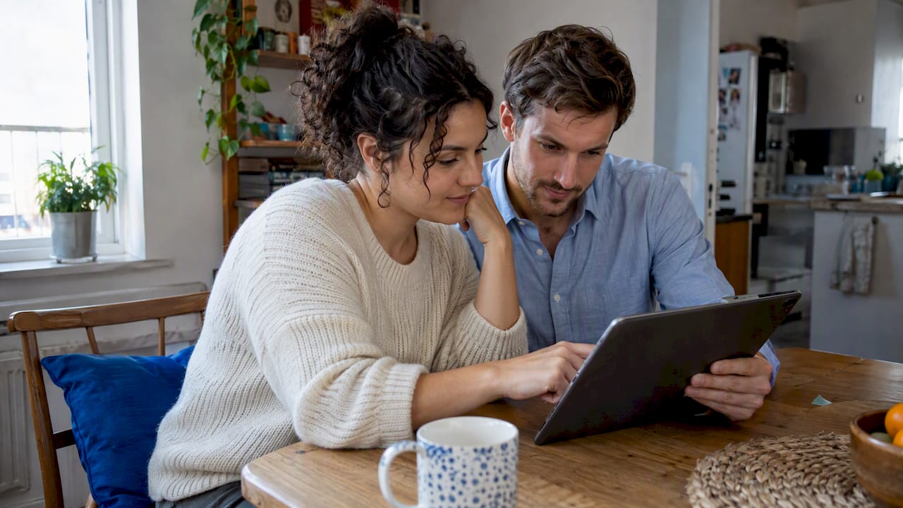 Couple comparing honeymoon trip options at home